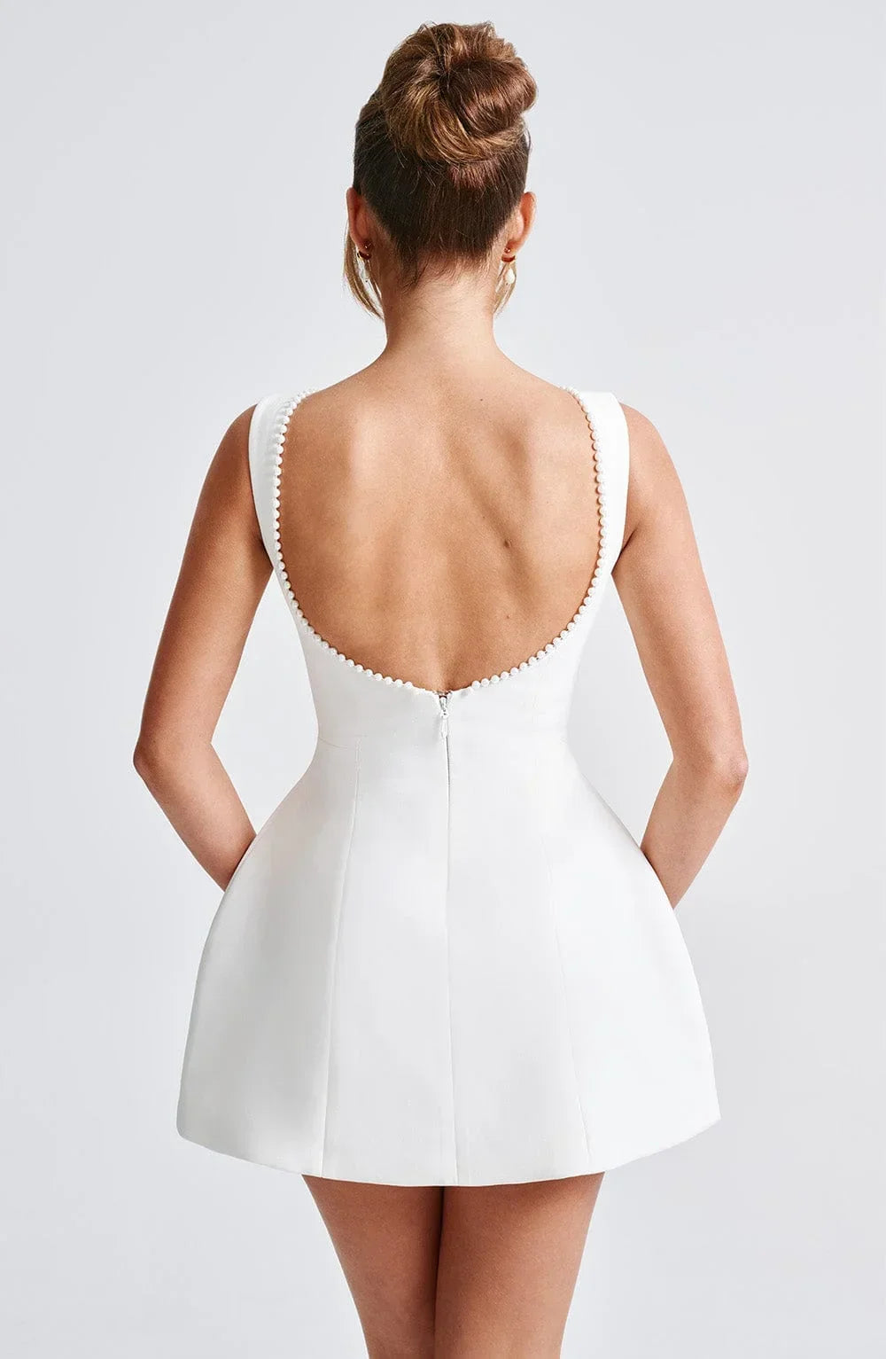 Vestito corto da donna con schiena nuda, dettaglio perlato e fiocco
