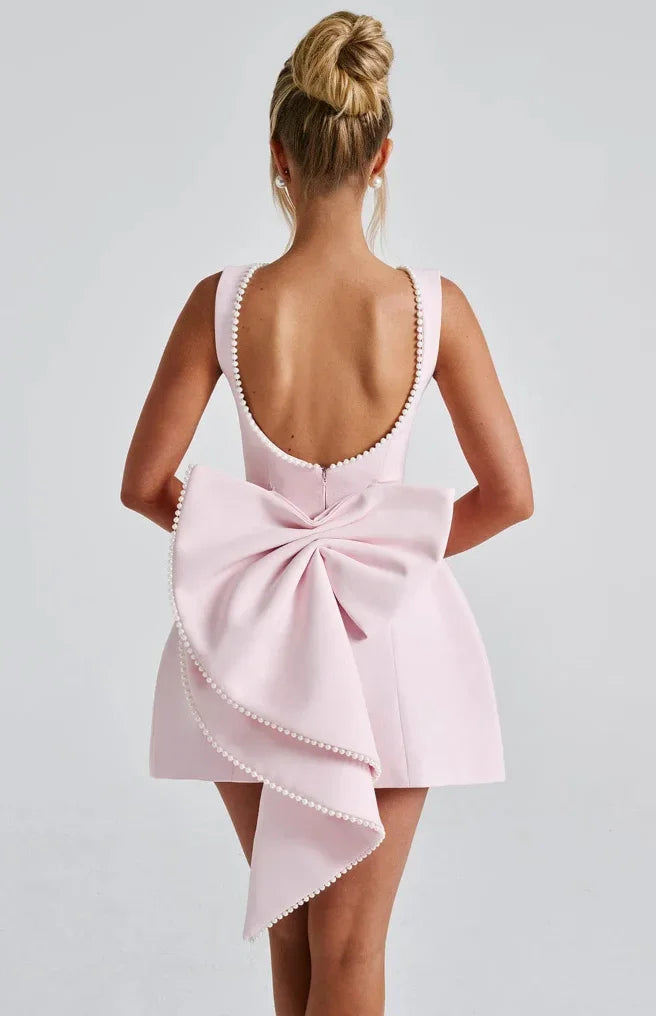 Vestito corto da donna con schiena nuda, dettaglio perlato e fiocco