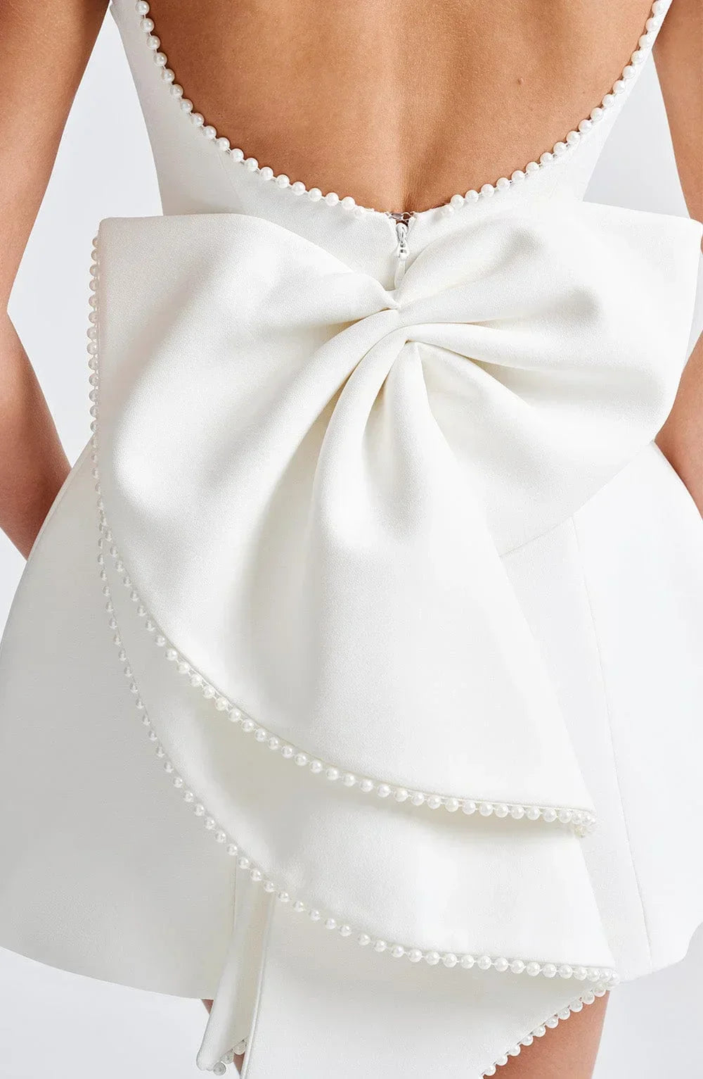 Vestito corto da donna con schiena nuda, dettaglio perlato e fiocco